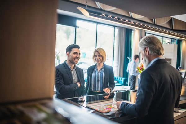 Hotelier reviewing data as 2 guests check in