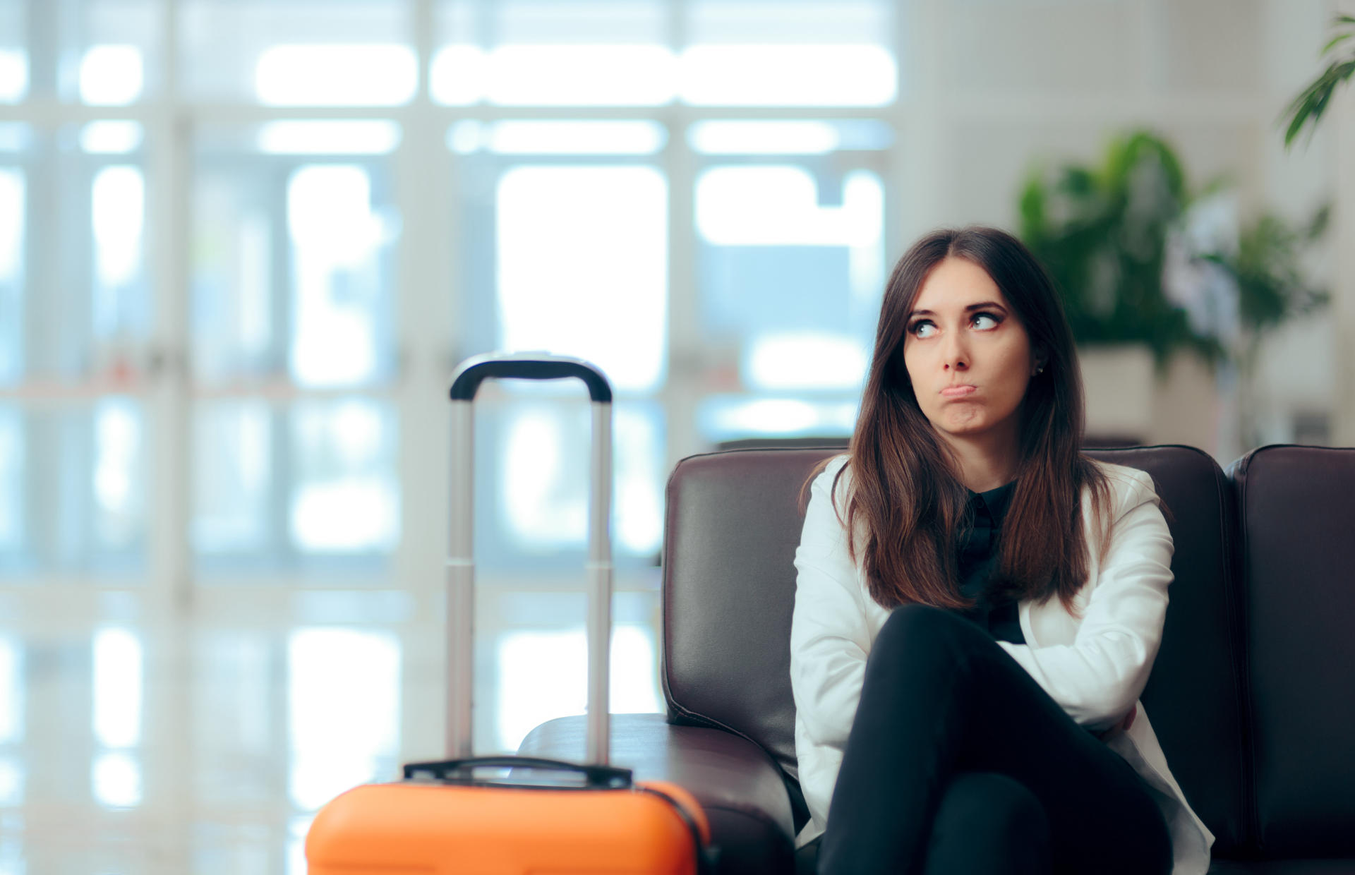 A person looks annoyed as they wait with their luggage.