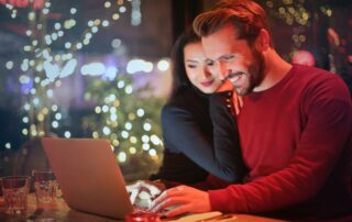 A couple reads Black Friday emails together, with holiday decorations in the background