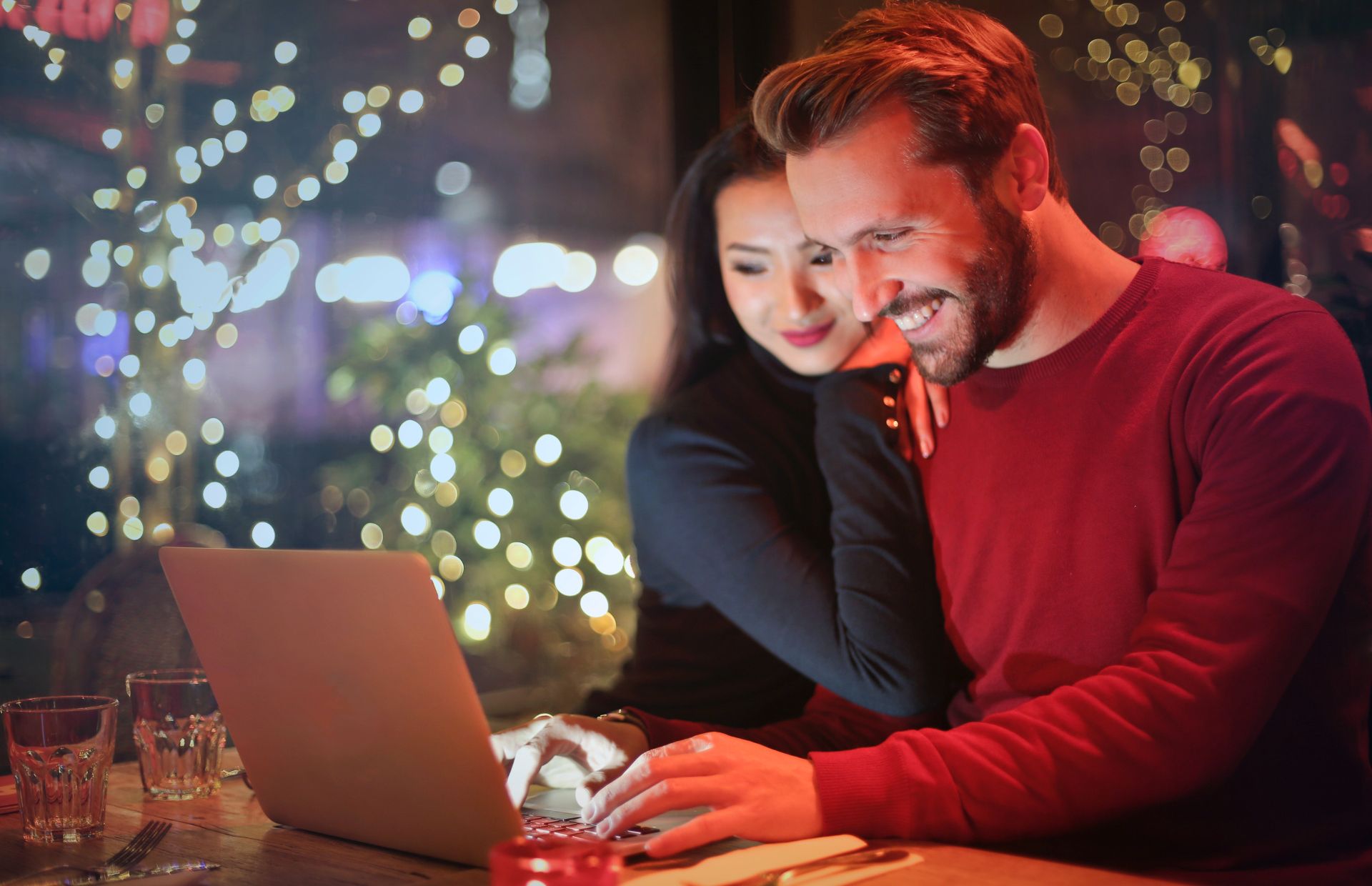 A couple reads Black Friday emails together, with holiday decorations in the background