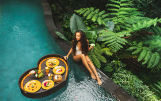 A person sits by the pool with a drink in their hand.