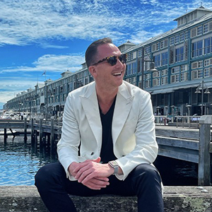 Stephen-Howard Headshot of Stephen Howard from Ovolo Hotels wearing sunglasses and a white jacket.