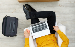 A business person sits in a chair with their laptop.