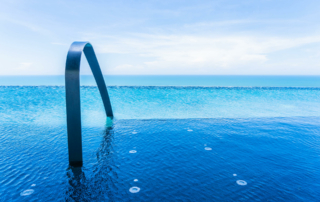 An outdoor hotel pool overlooks the ocean.