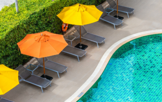 Orange and yellow umbrellas line a hotel pool.