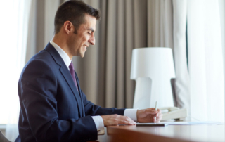 A business person sits at a hotel room table.