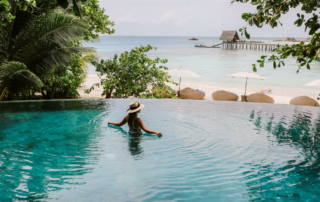 A person wades in the pool that overlooks the ocean.