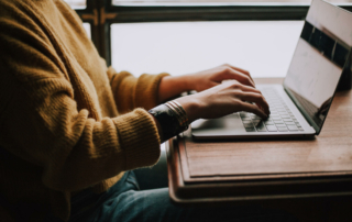 A person sits and types on their computer.