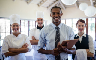 A group of hotel staff members stands and smiles.