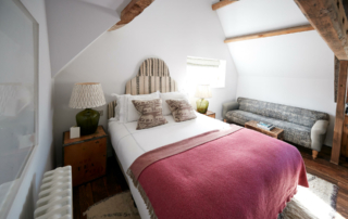 A hotel room is decorated with a bed, couch, and nightstand.