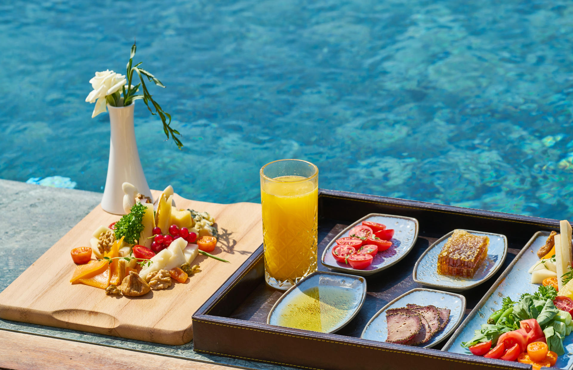 A tray of food lays on the edge of a pool.