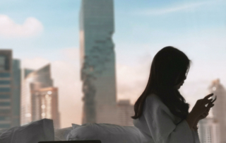 A guest sits on a hotel bed and looks down at their phone.