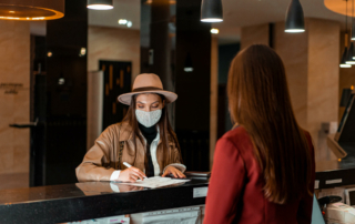 A guest wearing a mask checks in at the front desk.