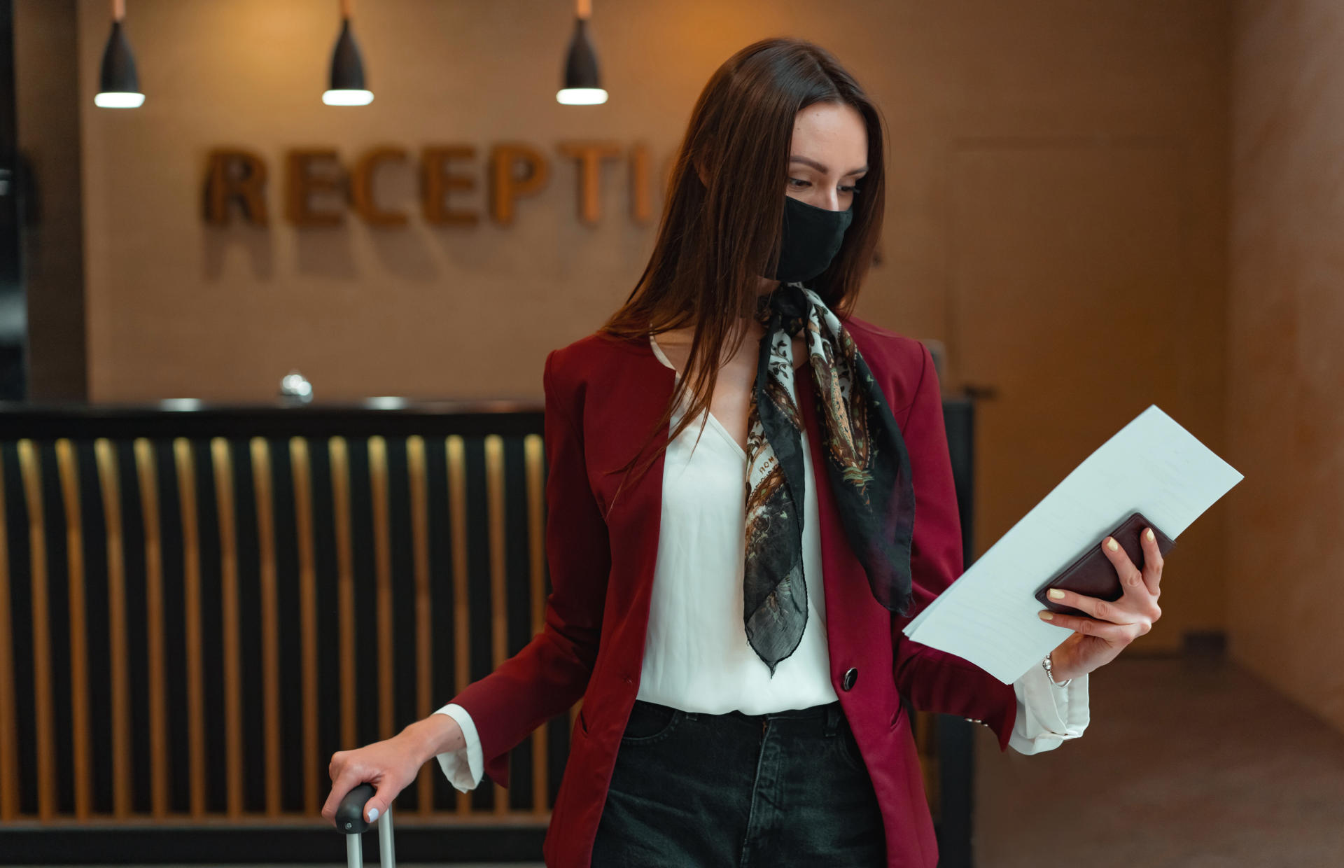 A hotel guest in a mask looks down at a piece of paper.