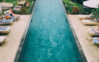 An aerial view of a hotel pool shows guests relaxing in pool chairs.