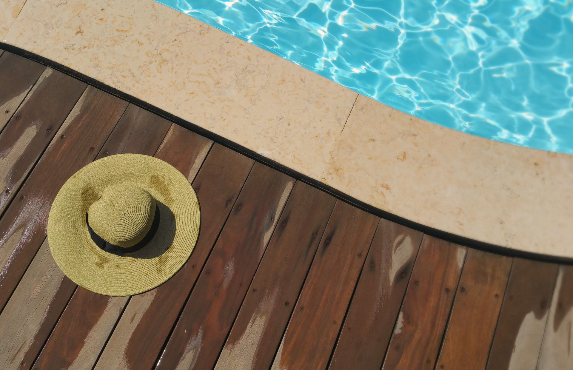 A sun hat lays on a pool deck.