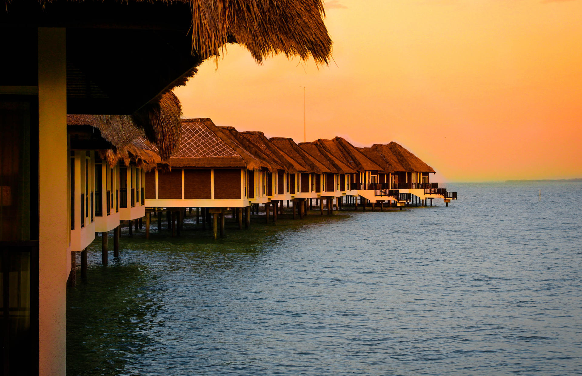 A string of resort villas stretches into the ocean.