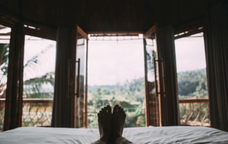 A guest lay down on a hotel bed and looks out the window.