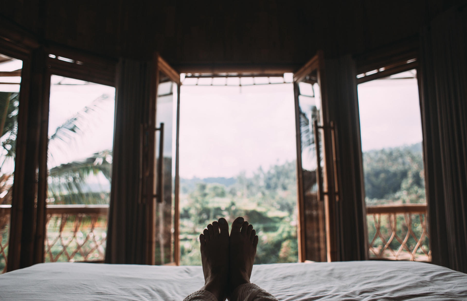 A guest lay down on a hotel bed and looks out the window.