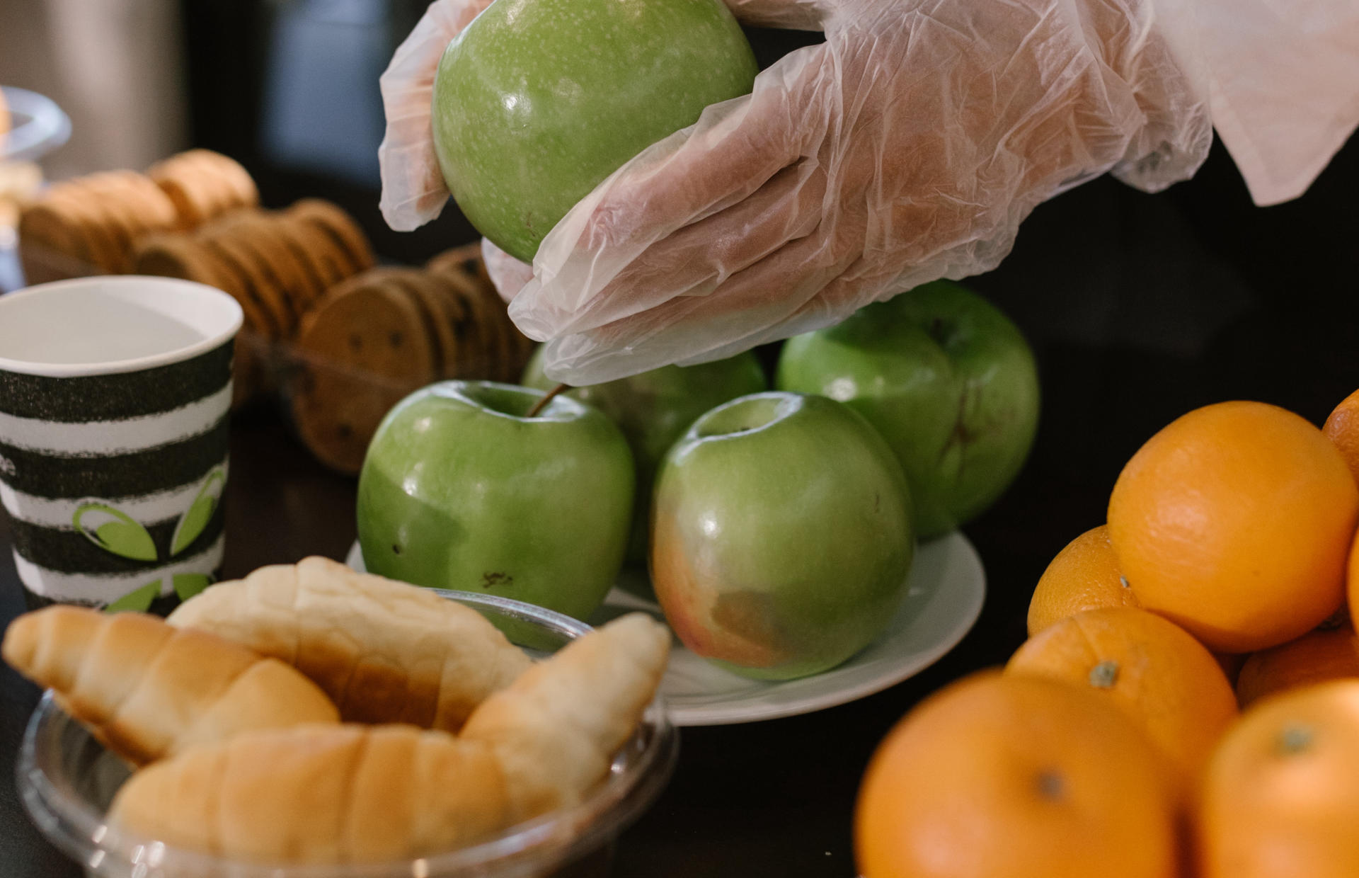 An apple is placed on a tray with gloved hands.