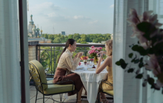 Two guests sit at a table on a hotel balcony.