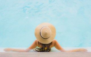 A woman in a sun hat wades at the end of the pool.