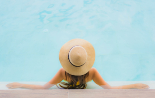 A woman in a sun hat wades at the end of the pool.