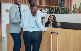 Two hotel guests are checking in at the front desk and speaking to the front desk staff.