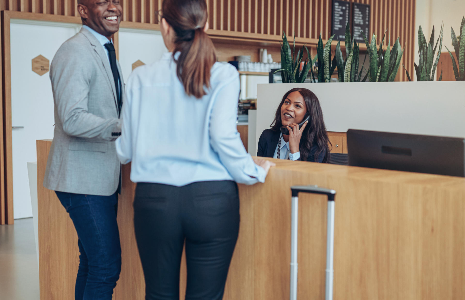 Two hotel guests are checking in at the front desk and speaking to the front desk staff.