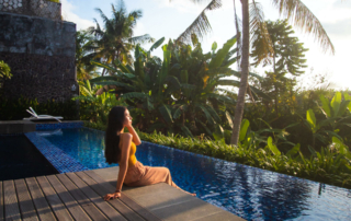 A woman is sitting on the edge of a hotel pool.