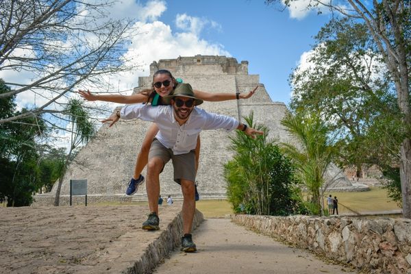 A couple poses for a fun photo in front of ancient ruins