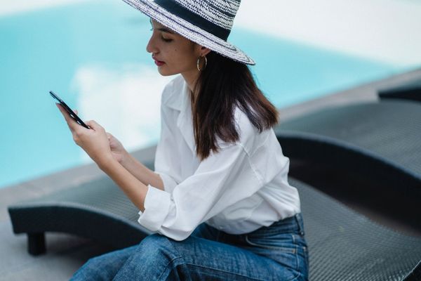 Woman using a text messaging solution by the side of a hotel pool