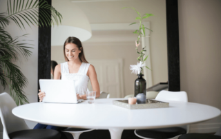 A woman sits a table in front of her computer.