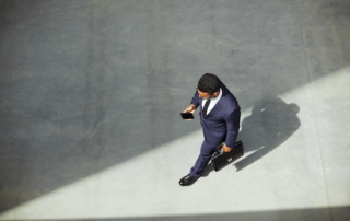 Man walking holding cell phone and briefcase.