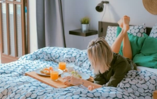 Woman eating breakfast in bed at a hotel.