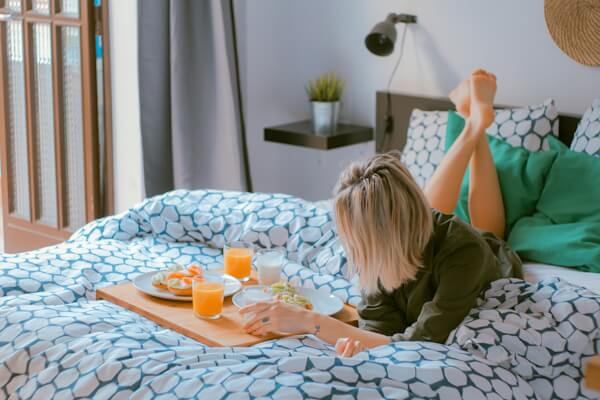 Woman eating breakfast in bed at a hotel.