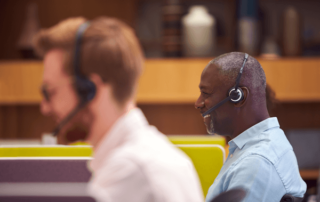 Mature male call center agents wearing headsets talking