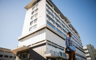 Man holding laptop standing by hotel
