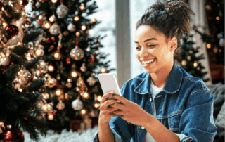 Woman on her phone in front of Christmas tree