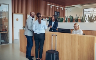 Man and woman speaking to hotel concierge front desk.