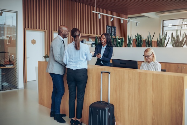 Man and woman speaking to hotel concierge front desk.