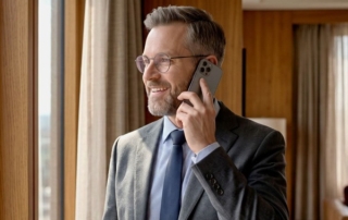Business man smiles while on cell phone in his hotel room.