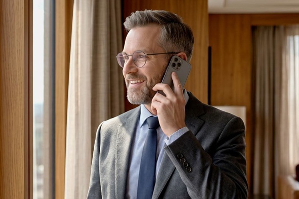 Business man smiles while on cell phone in his hotel room.