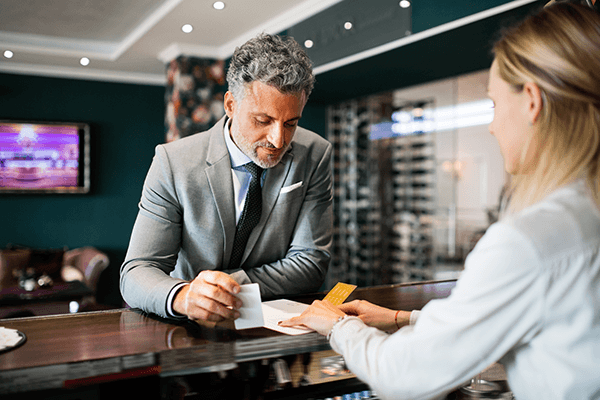 Older man checks in at hotel reception desk